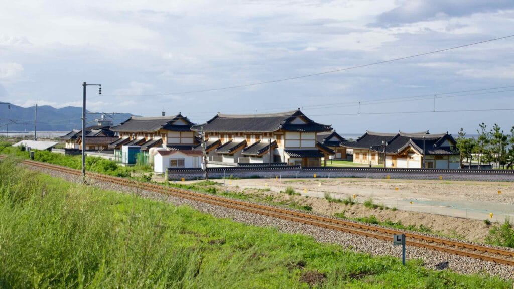 Revitalized Mangsang Beach Hanok Village showcases traditional Korean architecture with modern resilience against the backdrop of the East Sea, under a clear blue sky.