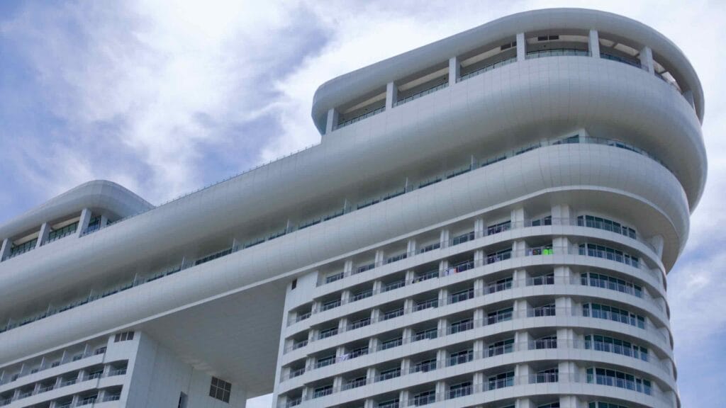 The top section of the Skybay Hotel Gyeongpo, showcasing its white facade, distinctive gap, and curvy lines against a clear blue sky.