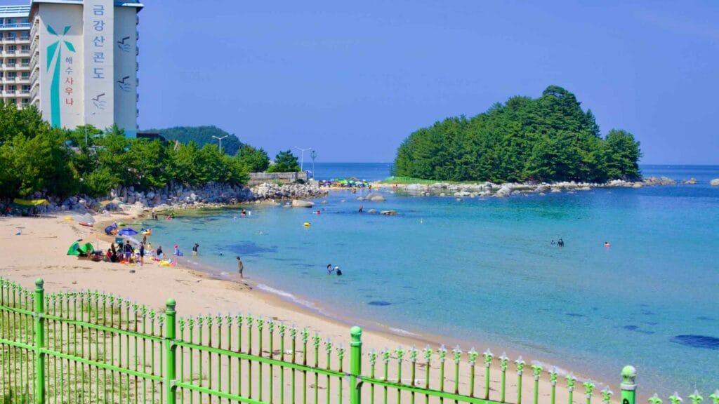 At Machajin Beach, a fence separates the road from the sandy shores where the Kumkangsan Condominium stands tall.
