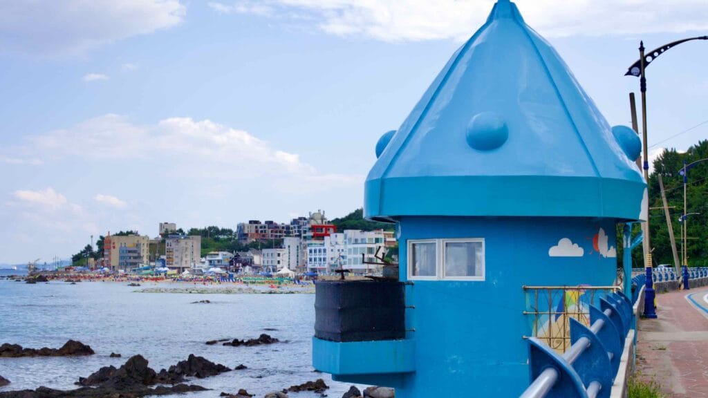 A distinctive sky-blue lookout post with a cone-shaped room stands along the seaside road of Eodal Port.