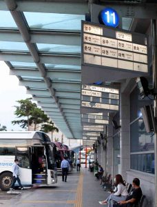 Platforms and signs listing destination cities at a Korea intercity bus terminal.
