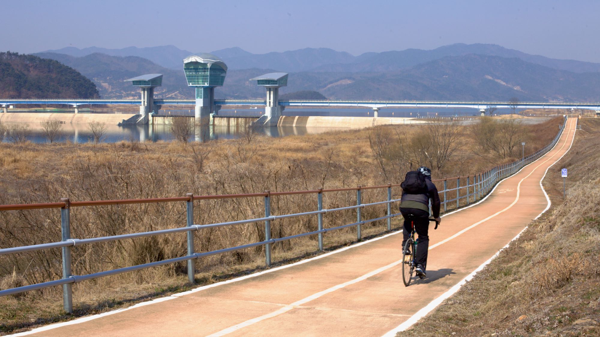 A picture of a rider and Gumi Weir along the Nakdonggang Bike Path (낙동강자전거길) in Gumi City on the Nakdong River (낙동강) in South Korea.