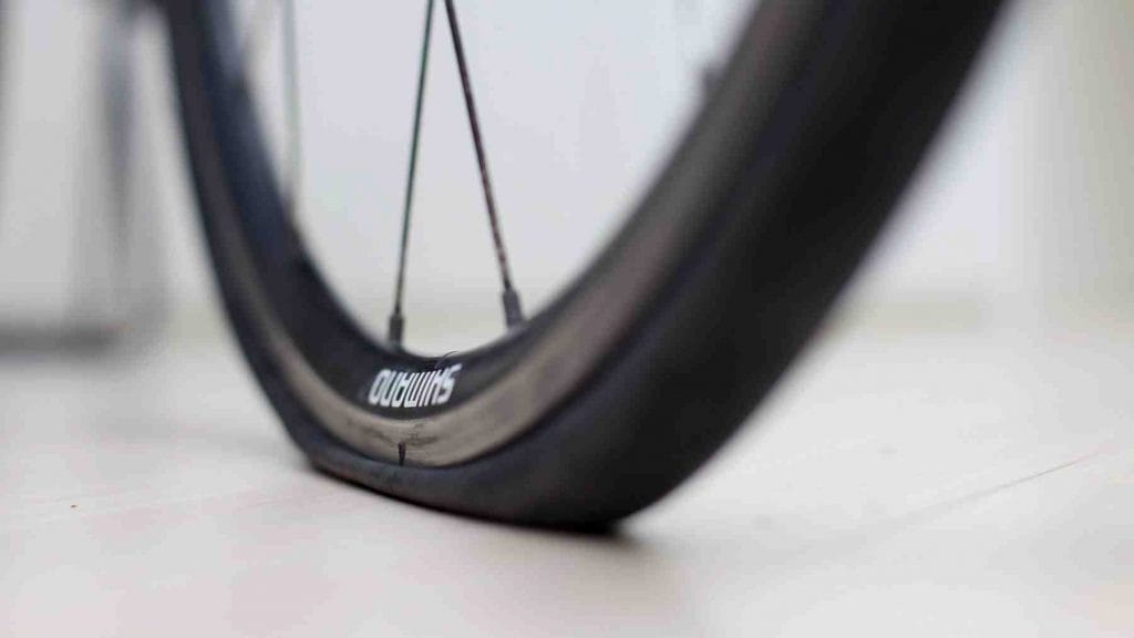 A close-up picture of a bicycle with a flat tire.