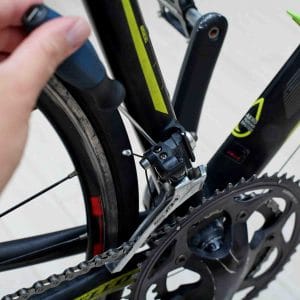 A picture of someone adjusting the limit screws on a bicycle's front derailleur.