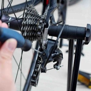 A picture of a screwdriver turning the limit screws on a bicycle's rear derailleur.