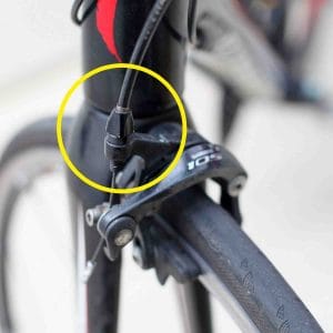 A picture of bicycle rim brakes with the barrel adjuster circled.