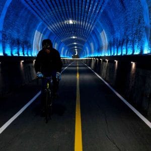 A picture of a cyclists riding through the decommissioned train tunnels of the Namhangang Bicycle Path.