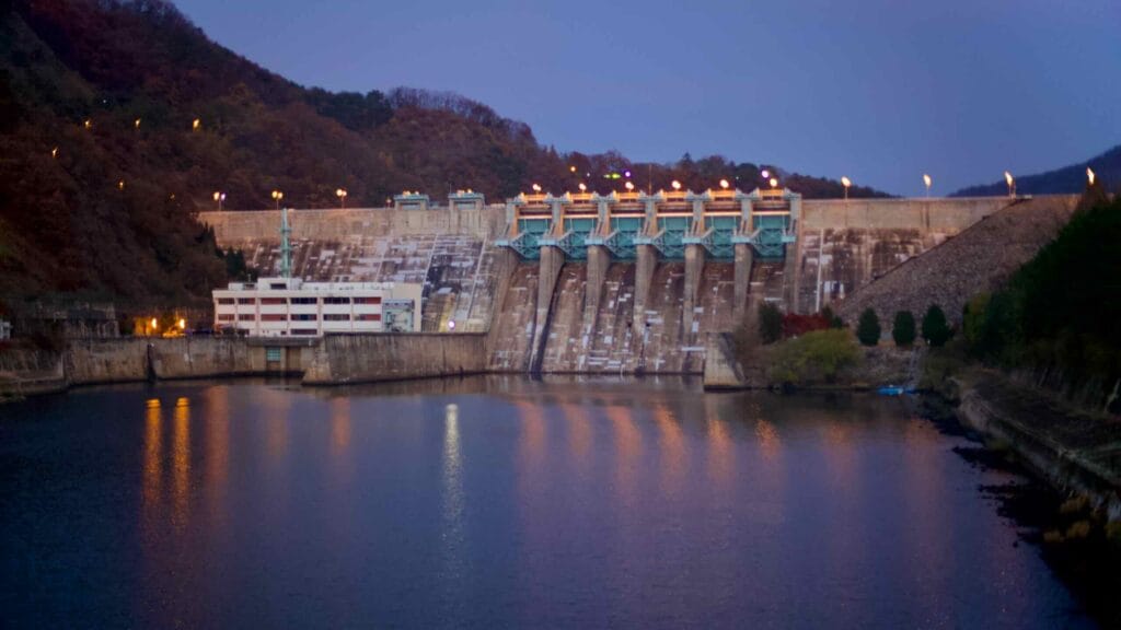 The Daecheong Dam illuminated at twilight, with its floodgates and hydroelectric facility on the Geum River.