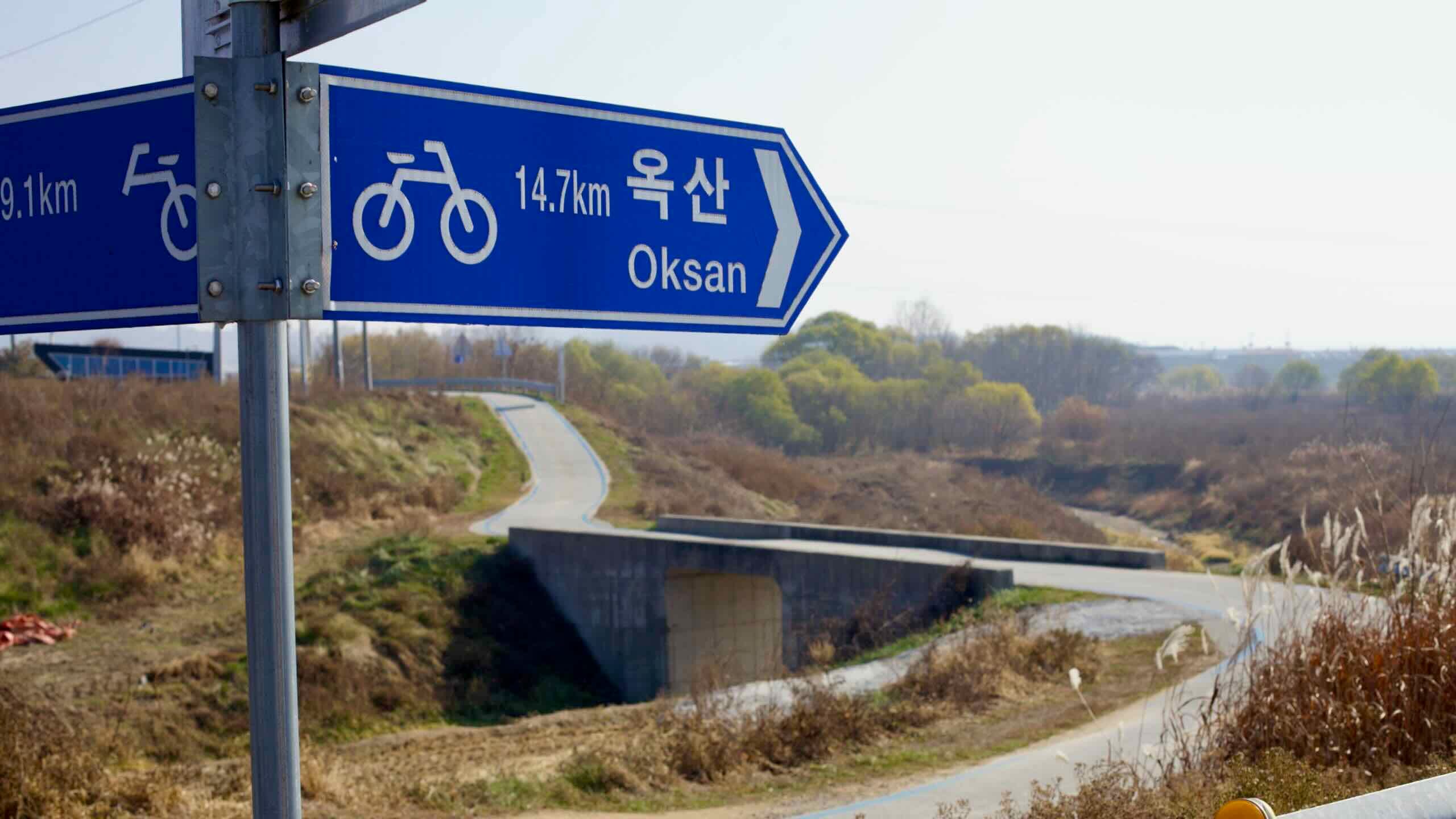 A cycling route sign pointing 14.7 km to Oksan along the Ocheon Bicycle Path.