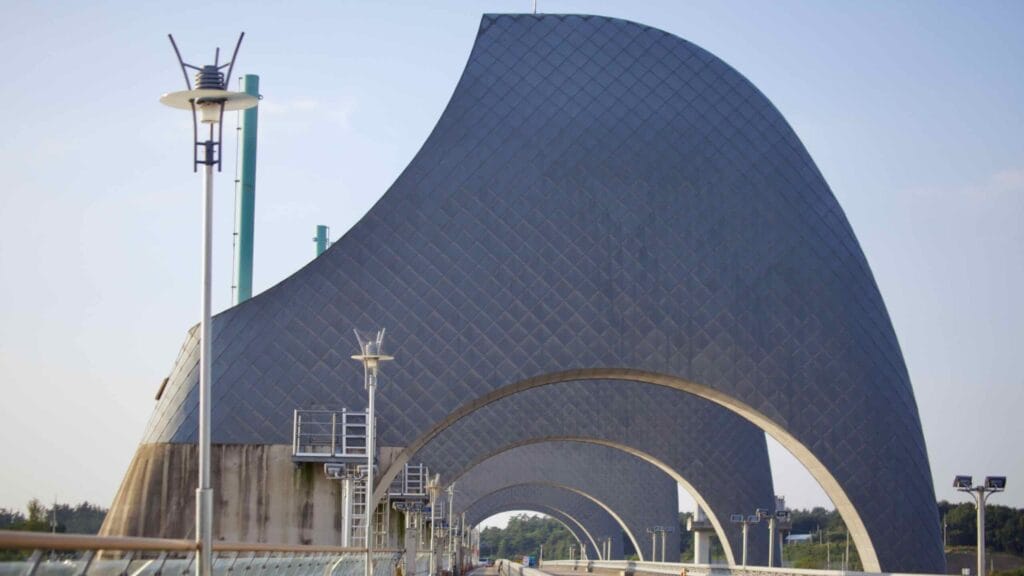 A path runs beneath the towering rice grain-shaped arches of Seungchon Weir.