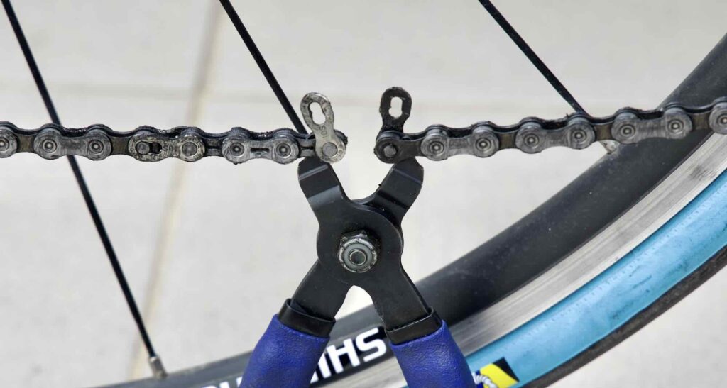 A picture of quick links and chain pliers on a bicycle chain.