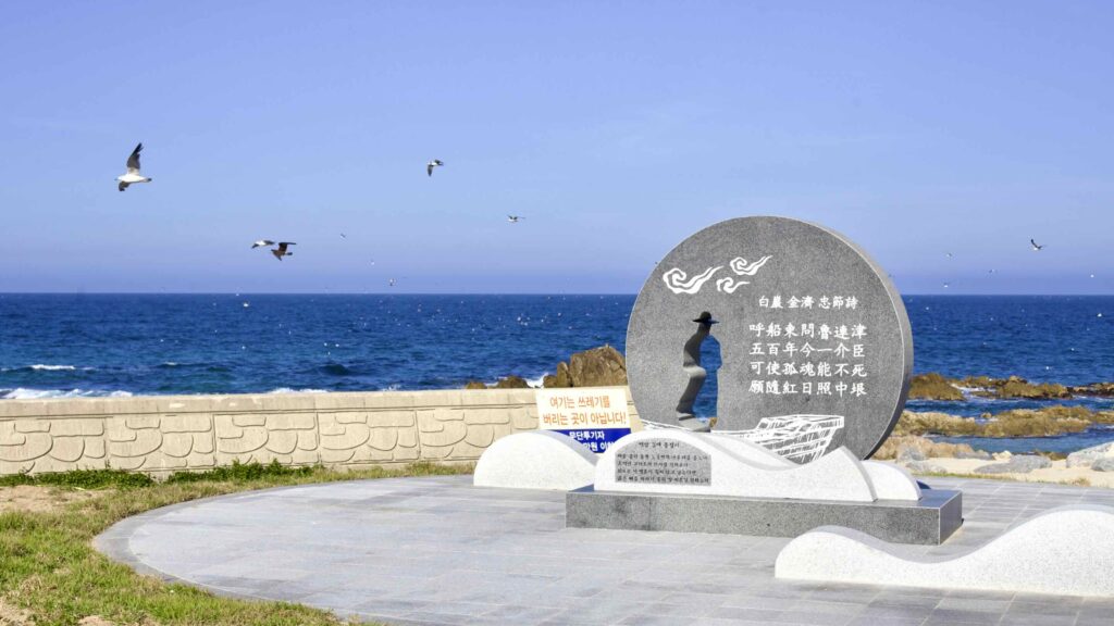 A picture of a round black near Gusan Port that tells the story of Baekam, who said he could not serve two kings and gave himself to the sea.