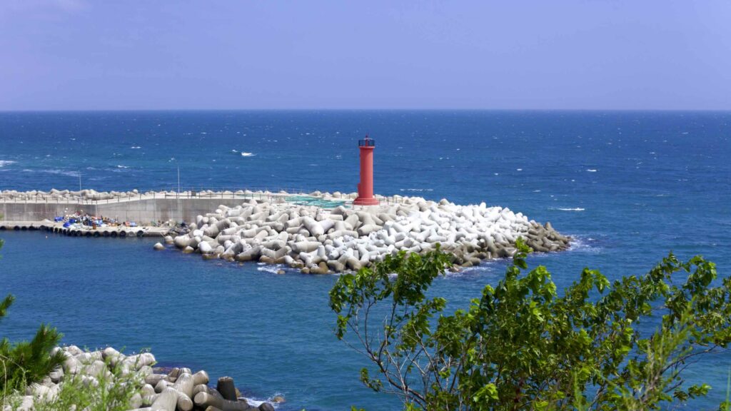 A picture of a lighthouse and breakwater at Nomul Port (노물항) in Yeongdeok County, South Korea.