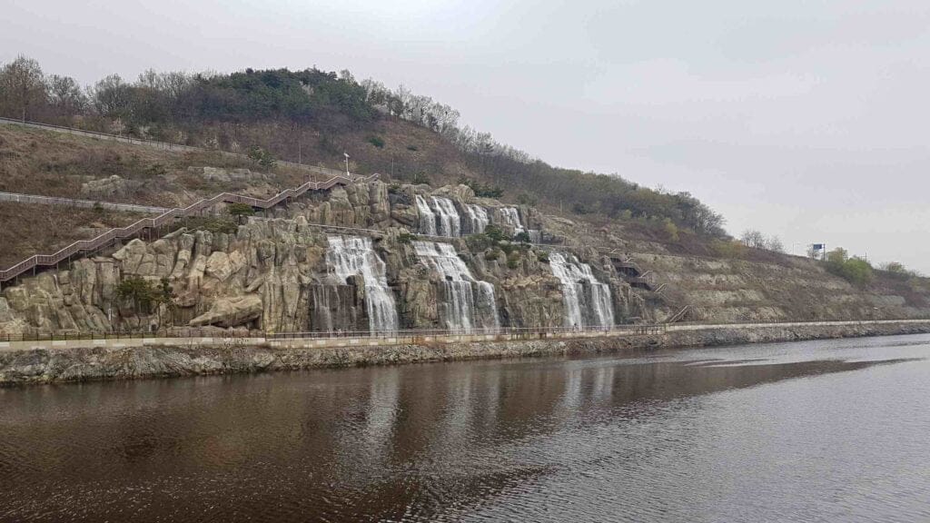 The engineered Ara Falls, inspired by the Joseon Dynasty's "After the Rain at Mount Inwang" painting, cascade along the bike path.