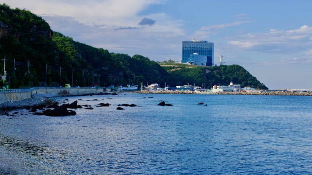 The sleek, glass-faced Tops 10 Hotel & Resort, a 15-story building on a seaside hill, overlooks Geumjin Port with the blue sky and East Sea waters enhancing its majestic presence.