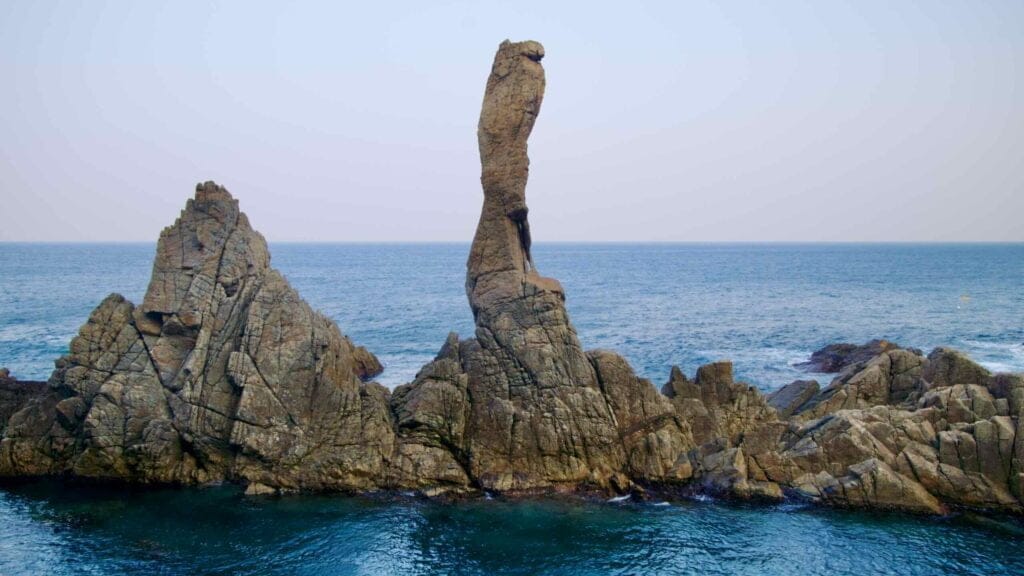 From a viewing platform on the Chogok Yonggul Cave Hiking Trail, the Candlestick Rock stands tall and thin, protruding from the East Sea surrounded by other rocks.