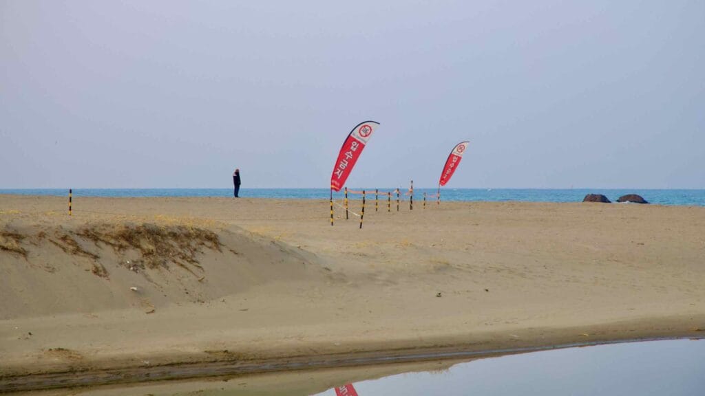 Near sunset, Maengbang Beach by Deokbong Mountain exudes calm, with an empty beach and a solitary figure standing in the distance, embracing the tranquil scene.