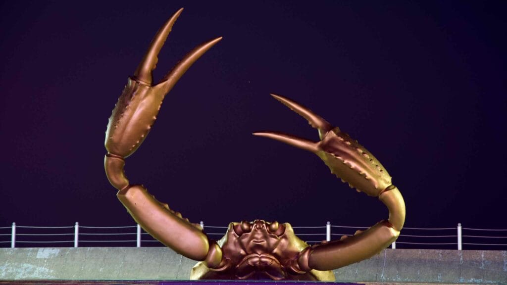 The imposing snow crab sculpture stands tall in Haeparang Park, set against the stark contrast of the black night sky, embodying the spirit of the coastal region.