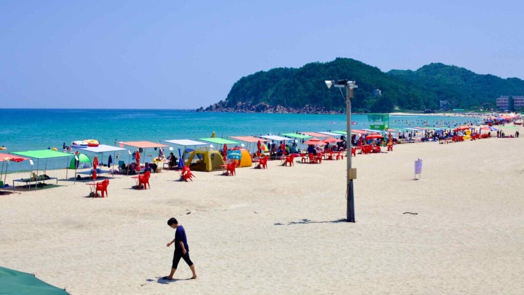 The pristine sands of Hwajinpo Beach unfold towards the seaside mountains.