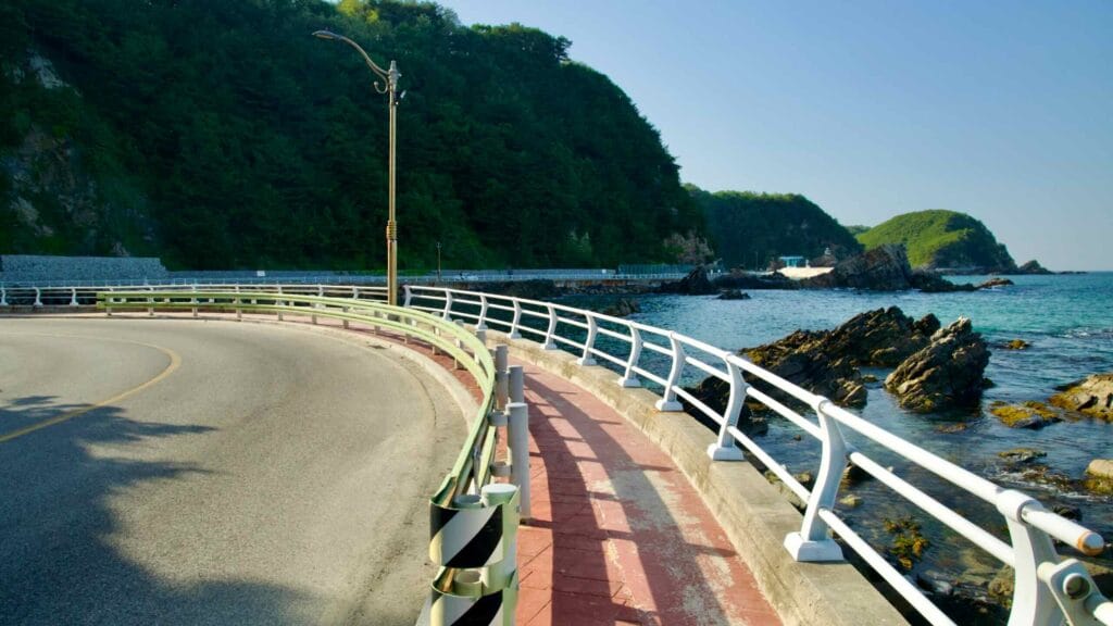 Heonhwa Road curves along the rocky coast of the East Sea, with a walkway and protective guardrails.