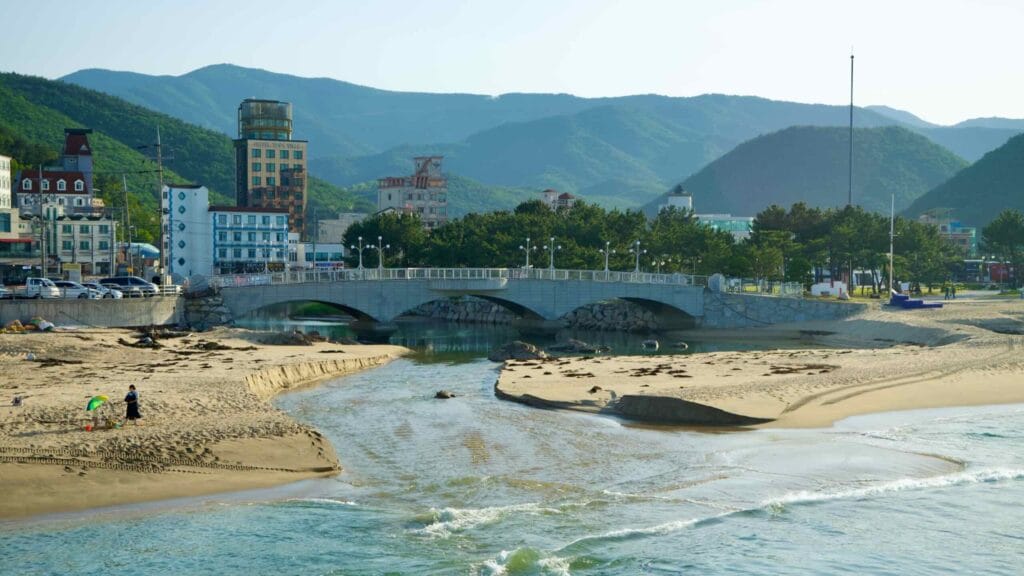 A view of a stream cutting through Jeongdongjin Beach, flowing under a bridge.