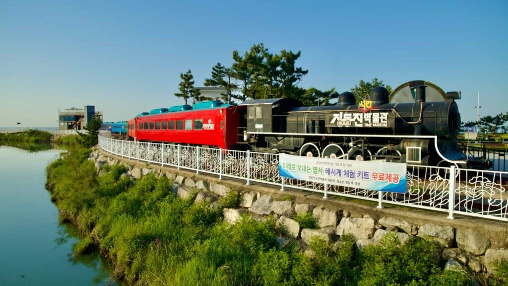 The Jeongdongjin Time Museum features a historic train exhibit, with colored passenger cars and a classic steam locomotive.