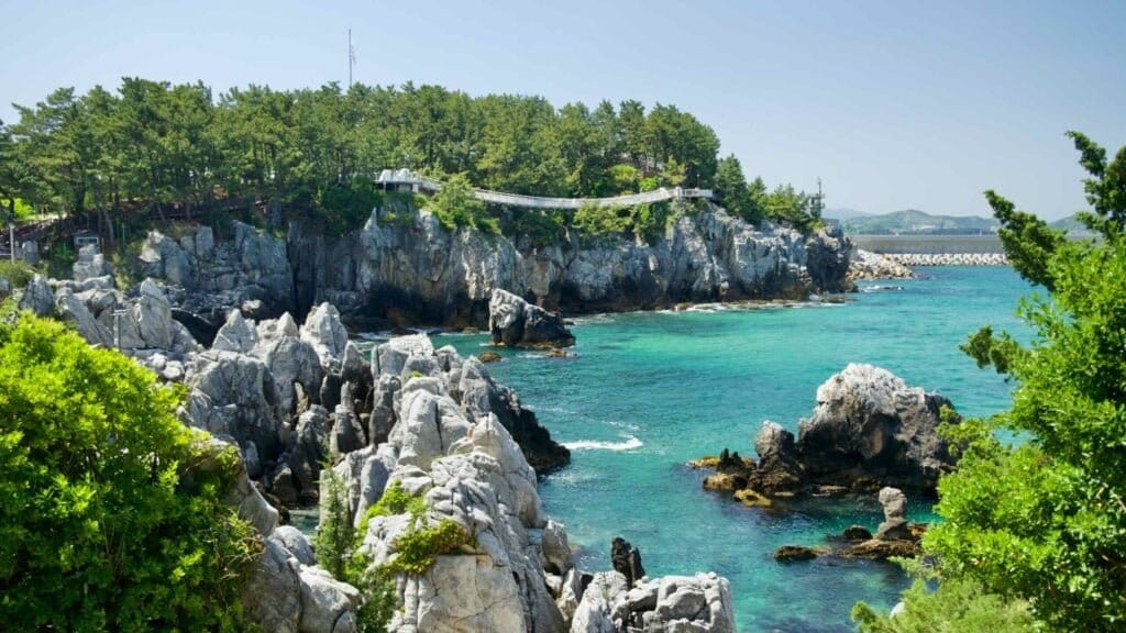 A view of the rugged coastal cliffs and Chuam Suspension Bridge spanning above.