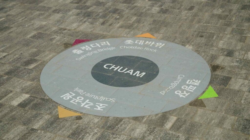 A directional sign on the pavement in Chuam, guiding visitors to various attractions including Candlestick Rock.