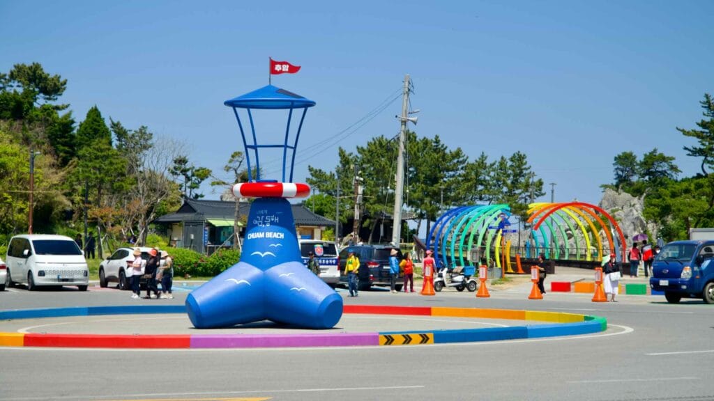 The entrance to Chuam Beach features a playful lighthouse sculpture and vibrant rainbow arches.