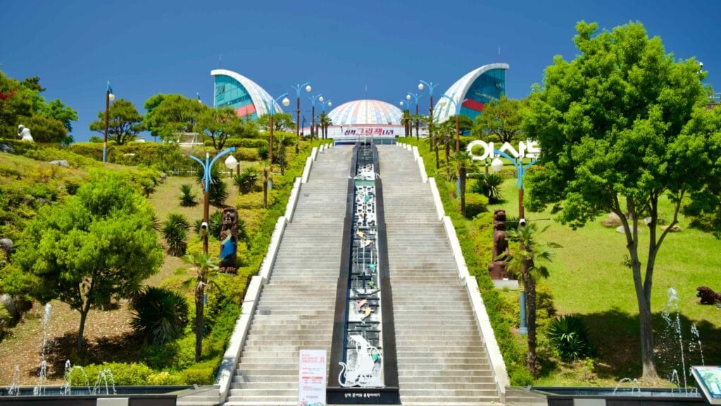 The grand staircase leading to Isabu Lion Park & Picture Book Land, surrounded by sculptures under a clear blue sky.