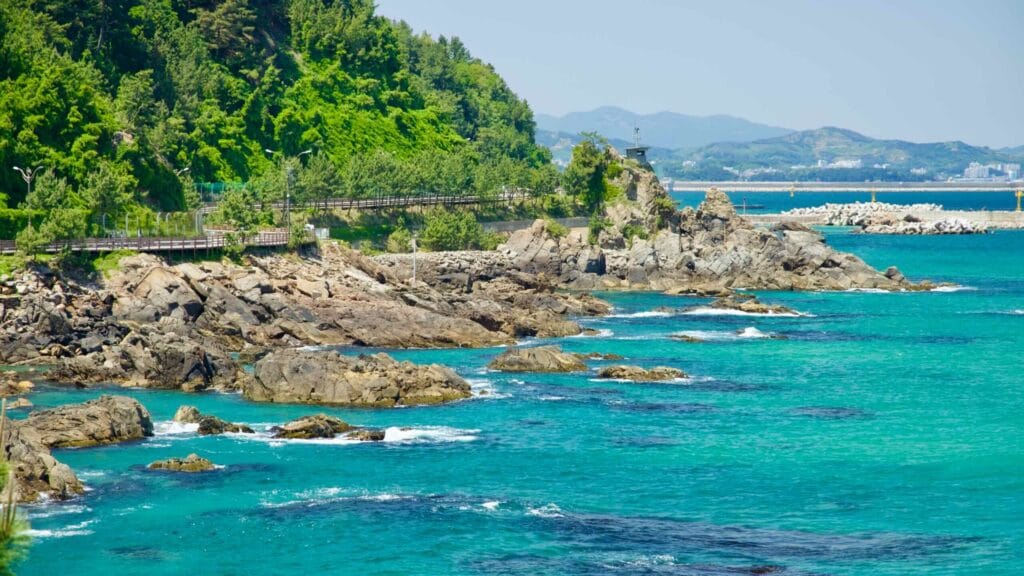 A scenic view of the rocky shoreline along Isabu Road, with waters and green hills from Beach Sculpture Park.