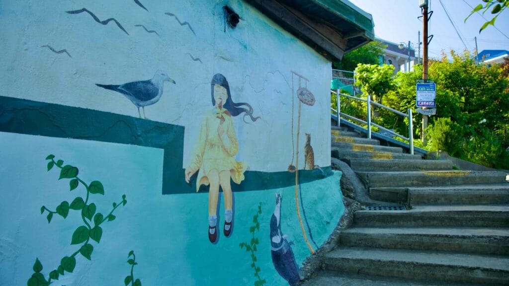 A mural featuring a girl, a cat, and a seagull adorns a wall on Nongoldam Street.