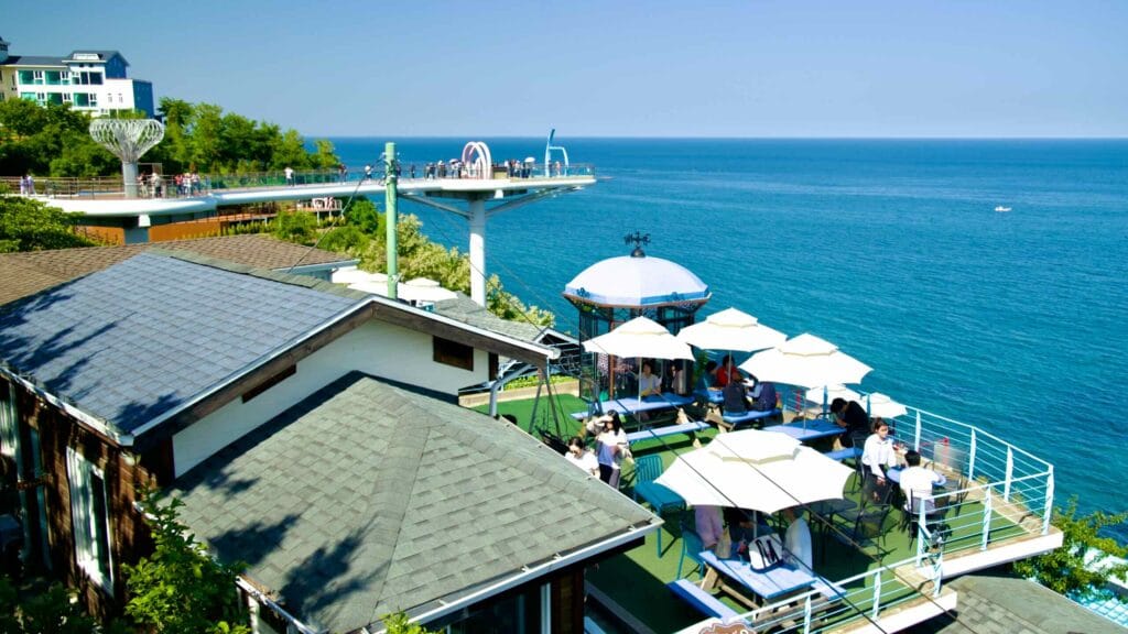 Patrons enjoy the outdoor seating area at Mukho Lighthouse Cafe, which provides stunning views of the East Sea.