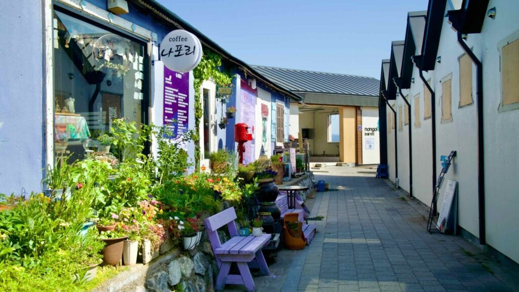 Shops and cafés line Nongoldam Street, adorned with vibrant flowers and local artwork.