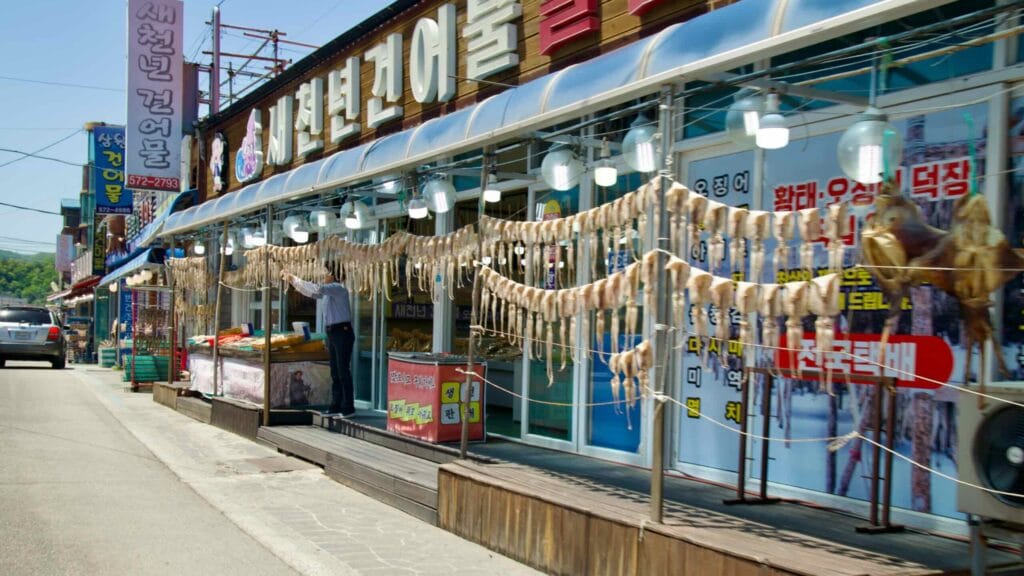 Rows of dried squid hanging outside a seafood shop at Samcheok Port, showcasing the local seafood market's offerings.