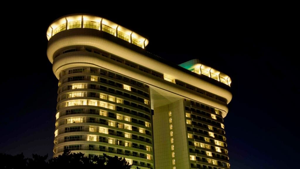 The Skybay Hotel Gyeongpo stands illuminated against the dark night, showcasing its unique architectural design and modern curves along the Gangneung coastline.