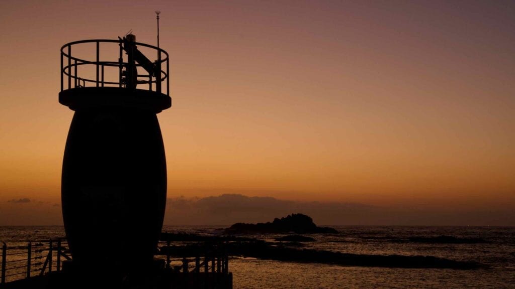 Silhouette of a lighthouse against the soft predawn sky at Muam Port.