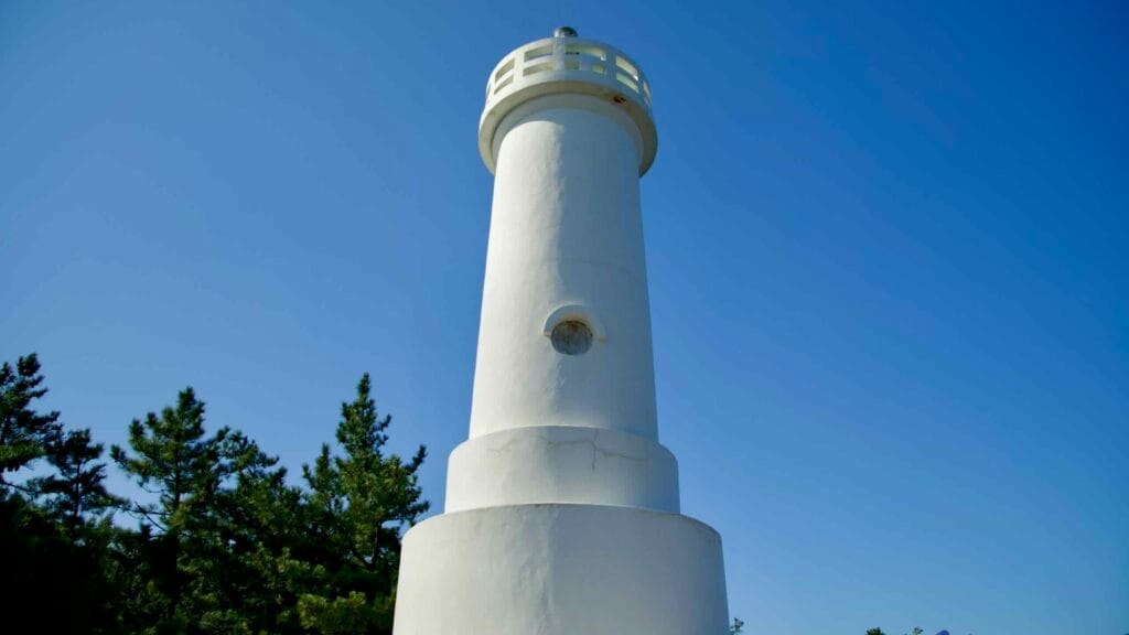 A close-up view of the Gisamun Lighthouse, also known as Hajodae Lighthouse. This coastal beacon stands tall against a vibrant blue sky.