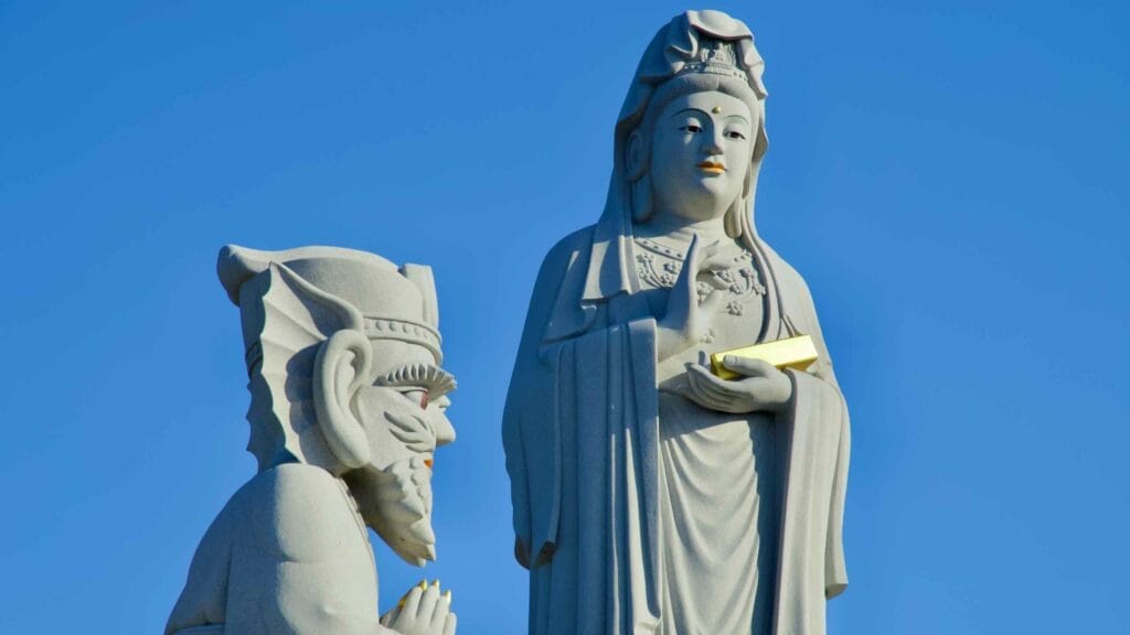 A detailed close-up of the Avalokitesvara statue and its guardian figure, highlighting intricate carvings and serene expressions at Huyuam Hermitage.
