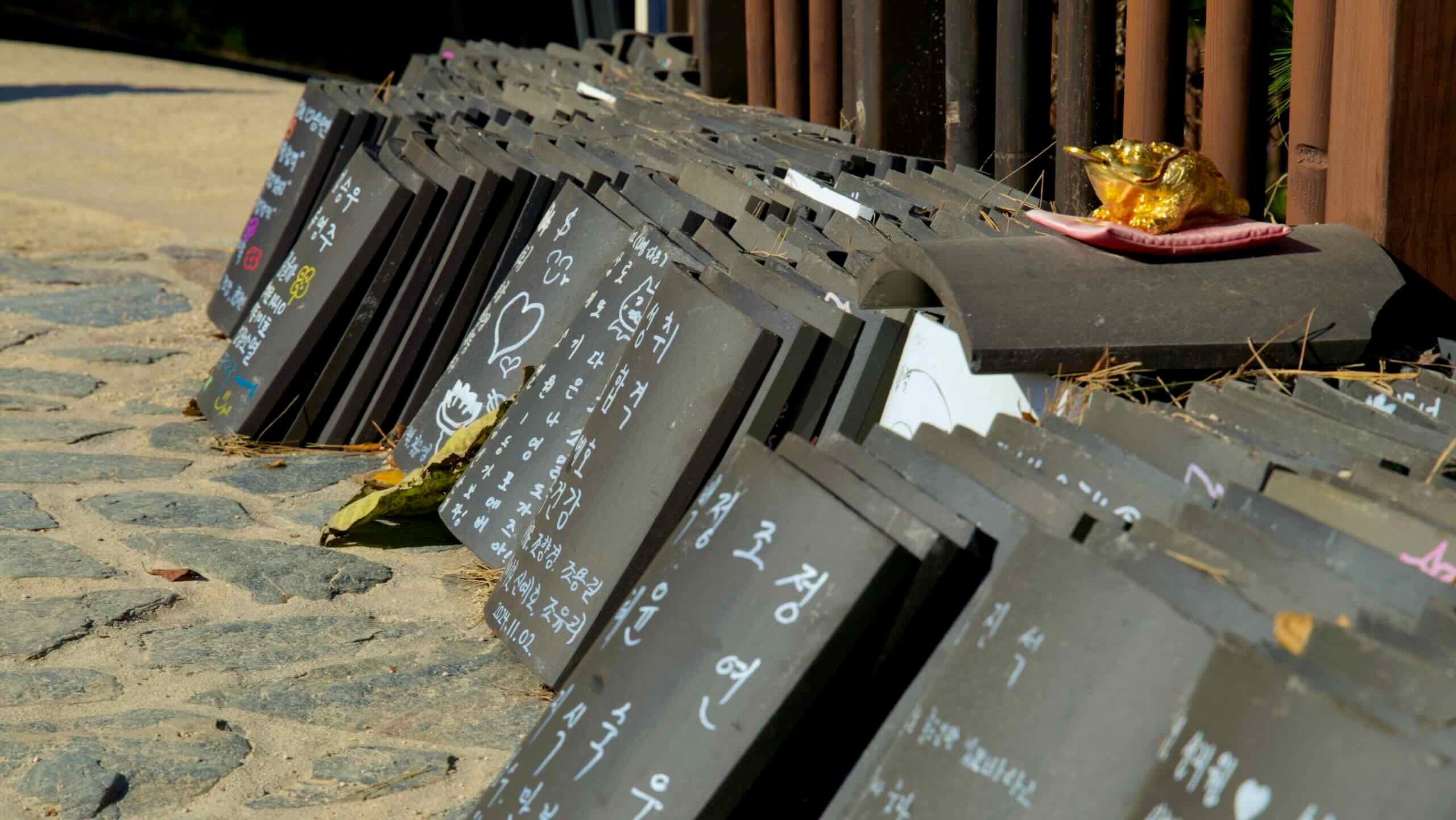 Rows of traditional roof tiles with handwritten messages of hope and prayer, left by visitors at Naksansa Temple as part of a cultural tradition.