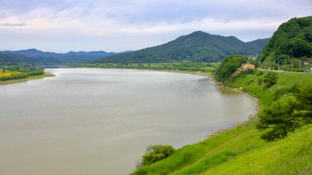 The Geum River winds through lush green hills under an overcast sky.