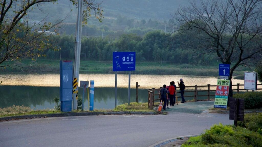 People gathered near the Seomjingang Bike Path entrance, enjoying the Seomjin River view.
