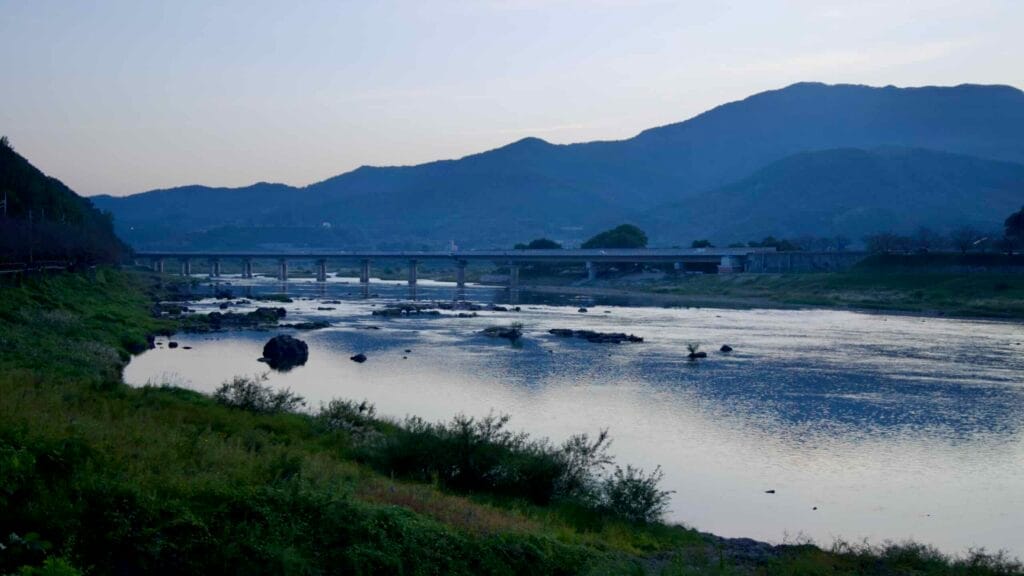 Serene Seomjin River at dusk, flowing calmly under a bridge and reflecting the fading light.