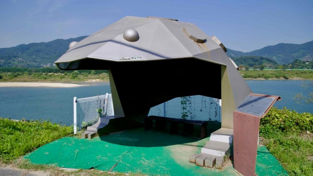 A designed frog-shaped rest shelter sits along the Seomjin River.