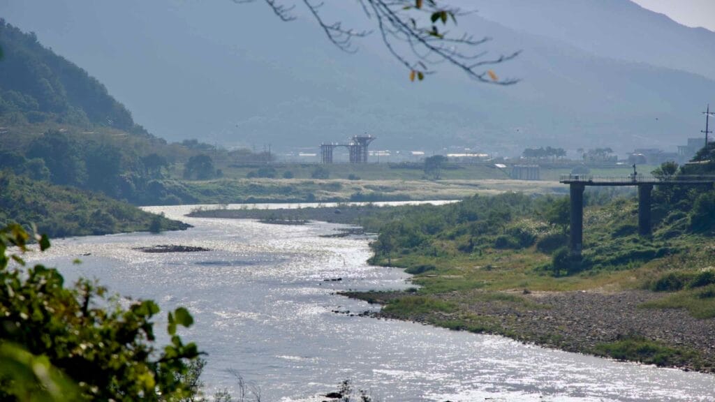 Seomjin River with shimmering sunlight and distant bridge construction.
