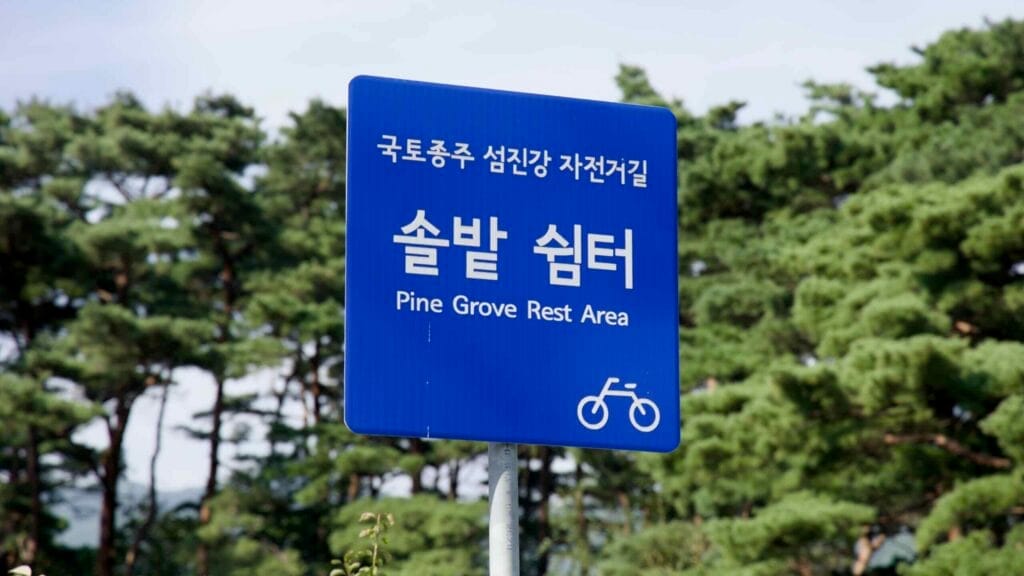 Blue directional sign for the Pine Grove Rest Area along the Seomjingang Bike Path.