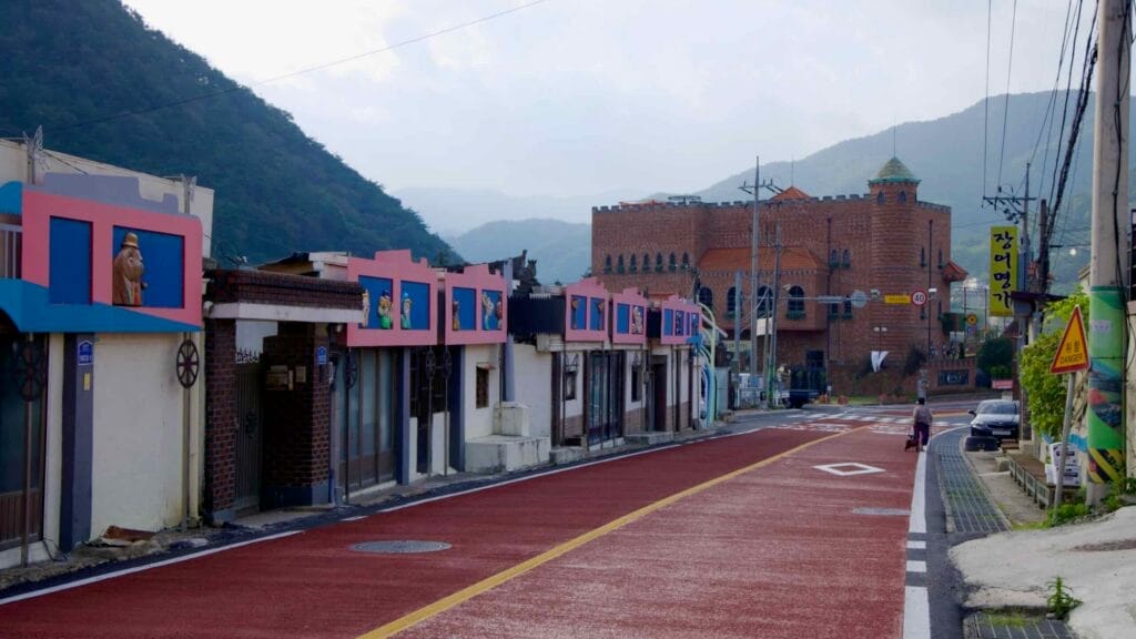 Colorful storefronts and a medieval-style building on a quiet street in Yalu Village.