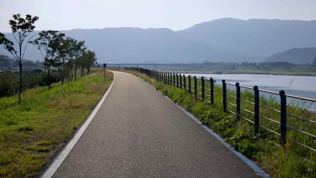 Paved bicycle path alongside a scenic river.