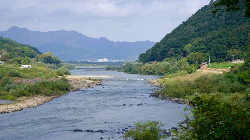 Seomjin River winding through a lush valley towards a distant cityscape.