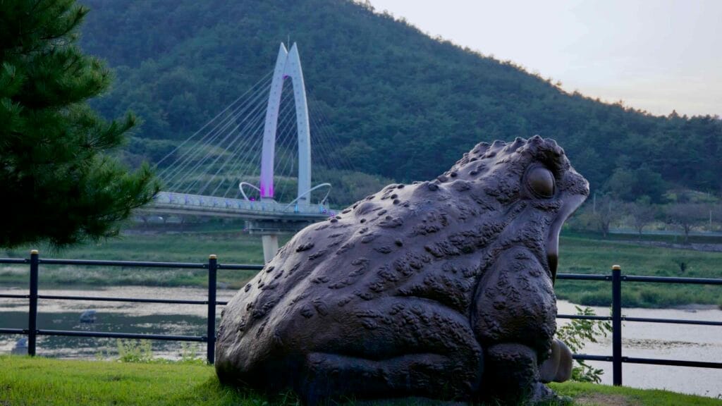 A toad statue sits near the Seomjin River, overlooking Toad Bridge.